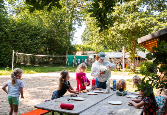 Kinderen doen buiten knutselwerk aan een tafel op Camping de Chênefleur, Luxemburg, België.