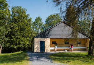 Camping de Chênefleur in Belgisch Luxemburg met mensen bij buitenwasbakken naast een gebouw.