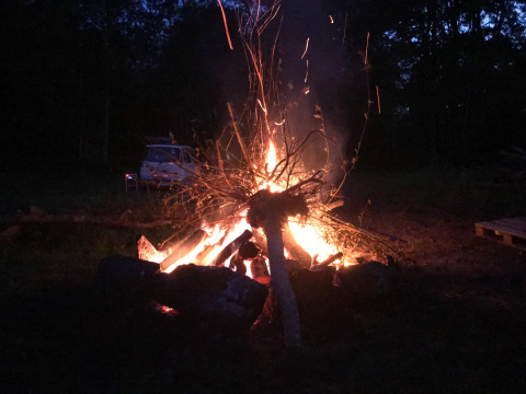 Un grande falò arde la notte al Camping de Chênefleur, Lussemburgo, Belgio, con un'auto sullo sfondo.