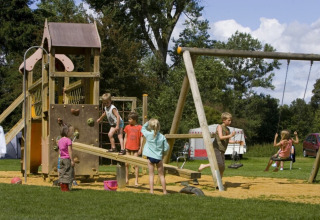 Bambini che giocano al parco giochi di Camping de Chênefleur in Lussemburgo, Belgio, circondati dal verde.