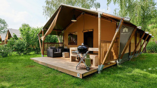 Tienda safari Villatent Nomad en Parc de Witte Vennen, Países Bajos, con terraza y barbacoa en césped.