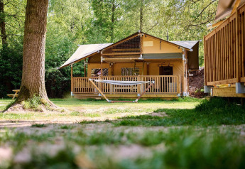 Tenda safari Villatent Ranger con amaca sull’erba al Recreatiepark de Lucht, Paesi Bassi, tra gli alberi