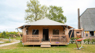 Tienda safari Villatent Cottage en Vakantiepark De Nollen, Países Bajos, vista frontal con porche y hamaca.