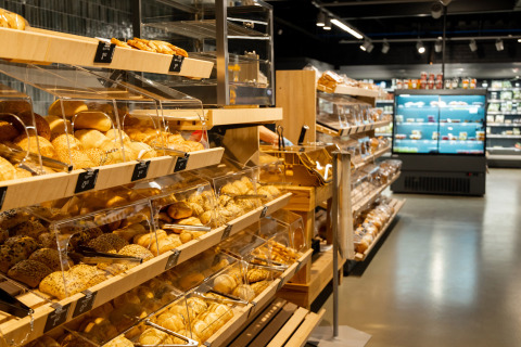 Sección de panadería en un supermercado de Vakantiepark de Twee Bruggen, Gelderland, con pan fresco y bollos expuestos.