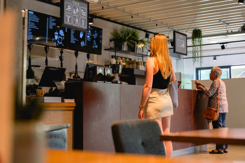 Donna che ordina al bancone in un caffè al Vakantiepark de Twee Bruggen, Gheldria, Paesi Bassi.