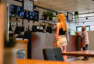 Kvinde bestiller ved skranken på en café i Vakantiepark de Twee Bruggen, Gelderland, Holland.