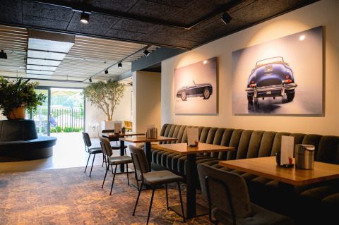 Zona de cafetería moderna en Vakantiepark de Twee Bruggen con arte de autos clásicos en la pared.
