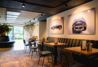 Moderne cafetaria in Vakantiepark de Twee Bruggen met kunst van klassieke auto’s aan de wand.