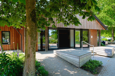 Entrance to a wooden holiday lodge surrounded by greenery at Vakantiepark de Twee Bruggen, Gelderland.