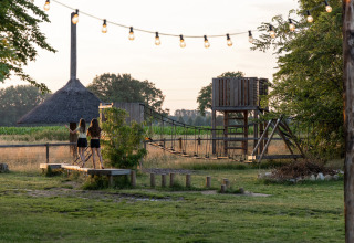 Zwei Mädchen auf einem Spielplatz mit Hängebrücke im Vakantiepark de Twee Bruggen, Gelderland, Niederlande.