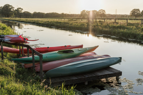 Des kayaks sur un ponton au bord d’un canal au coucher du soleil à Vakantiepark de Twee Bruggen, Gelderland.