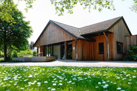 Wooden house at Vakantiepark de Twee Bruggen, Gelderland, Netherlands, with a flowered lawn in front.