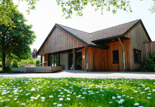 Wooden house at Vakantiepark de Twee Bruggen, Gelderland, Netherlands, with a flowered lawn in front.