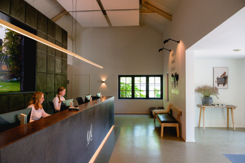 Área de recepción en Vakantiepark de Twee Bruggen en Gelderland, Países Bajos, con personal en el mostrador moderno.