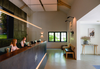 Área de recepción en Vakantiepark de Twee Bruggen en Gelderland, Países Bajos, con personal en el mostrador moderno.