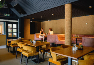 Moderne cafetaria met zachte zetels en houten tafels in Vakantiepark de Twee Bruggen, Gelderland, Nederland.
