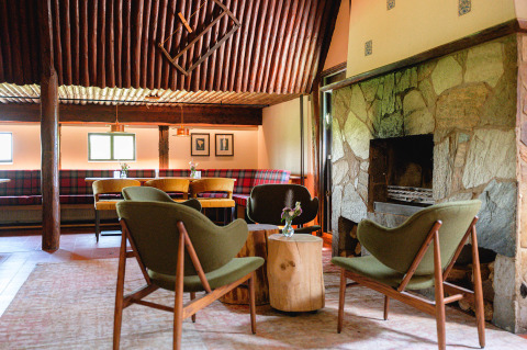 Hyggelig lounge ved pejsen i Vakantiepark de Twee Bruggen, Gelderland, med vintage stole og træborde.