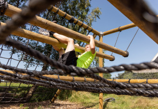 Man climbing on an outdoor obstacle course at Vakantiepark de Twee Bruggen in Gelderland, Netherlands.