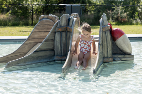 Niña pequeña deslizándose por un tobogán en la piscina de Vakantiepark de Twee Bruggen, Gelderland, Países Bajos.