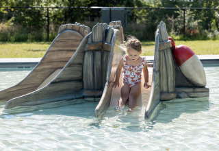 Niña pequeña deslizándose por un tobogán en la piscina de Vakantiepark de Twee Bruggen, Gelderland, Países Bajos.