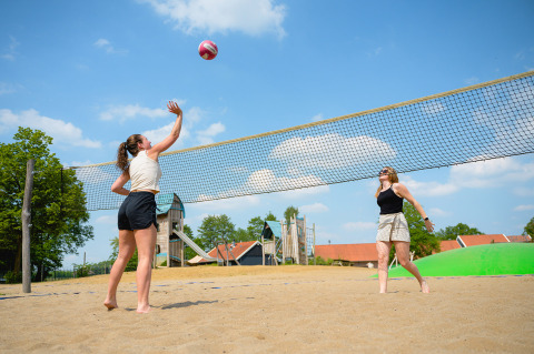 Two women play beach volleyball on a sunny day at Vakantiepark de Twee Bruggen in Gelderland, Netherlands.