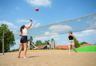 Two women play beach volleyball on a sunny day at Vakantiepark de Twee Bruggen in Gelderland, Netherlands.