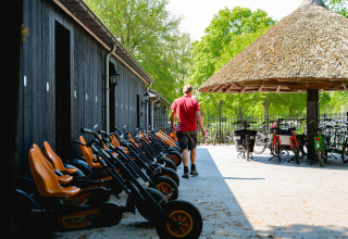 Een man wandelt tussen skelters en fietsen bij Vakantiepark de Twee Bruggen in Gelderland, Nederland.