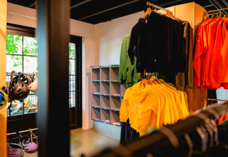 Binnen in een winkel in Vakantiepark de Twee Bruggen met kleurrijke truien en helmen uitgestald.