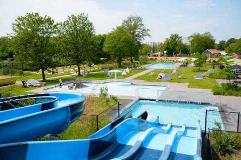 Piscina al aire libre con toboganes y césped en Vakantiepark de Twee Bruggen, Gelderland, Países Bajos.