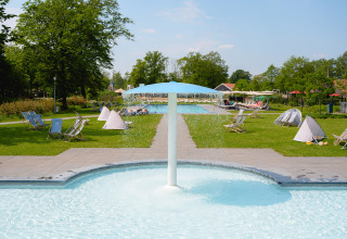 Outdoor swimming pool with fountain and sun loungers at Vakantiepark de Twee Bruggen in Gelderland, Netherlands.