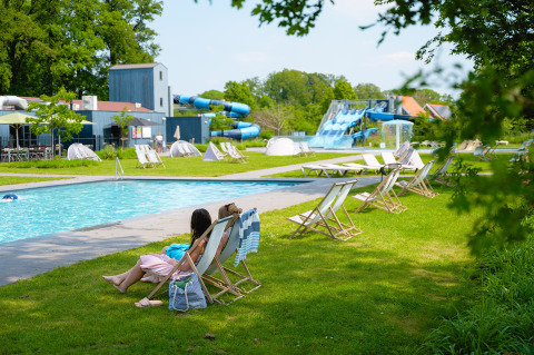 Pool area with lounge chairs and water slides at Vakantiepark de Twee Bruggen, Gelderland, Netherlands.
