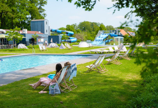 Schwimmbadbereich mit Liegestühlen und Wasserrutschen im Vakantiepark de Twee Bruggen, Gelderland.