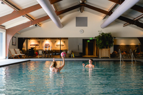 Due persone giocano con una palla in una piscina coperta al Vakantiepark de Twee Bruggen in Gelderland, Paesi Bassi.