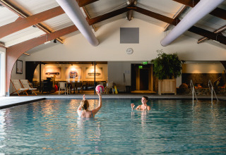 Zwei Personen spielen mit einem Ball im Hallenbad des Vakantieparks de Twee Bruggen in Gelderland, Niederlande.