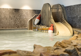 Indendørs swimmingpool med rutsjebane og bøjer i ferieparken Vakantiepark de Twee Bruggen, Gelderland.