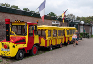 Small, colorful tourist train at Camping de Krabbeplaat holiday park, with two children walking by.
