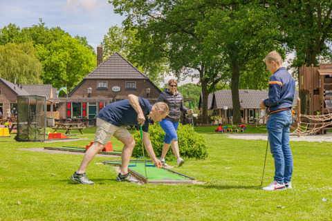 Familia juega al minigolf en Vakantiepark Sallandshoeve, parque vacacional en Overijssel, Países Bajos.