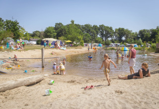 Kinderen en gezinnen genieten bij het meer van Vakantiepark Sallandshoeve, tussen tenten en natuurgroen.