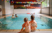 To små børn sidder sammen ved kanten af en indendørs swimmingpool i Vakantiepark Sallandshoeve, Overijssel.