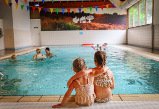 Twee kleine kinderen zitten samen aan het binnenzwembad van Vakantiepark Sallandshoeve in Overijssel.