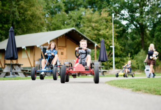Kinderen op gocarts voor lodge-tenten in Vakantiepark Sallandshoeve, Overijssel, Nederland.