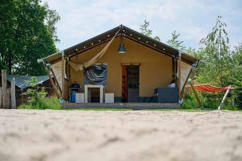 Tienda safari Villatent Nomad en Vakantiepark Sallandshoeve, Países Bajos, con hamaca y terraza exterior.