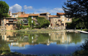 Malermesterudsigt over charmerende rækkehuse langs en flod i Camping De l'Olivigne, Occitanie, Frankrig.