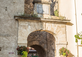 Historisk stenport med buet gangbro ved Camping De l'Olivigne, en feriepark i Occitanie, Frankrig.