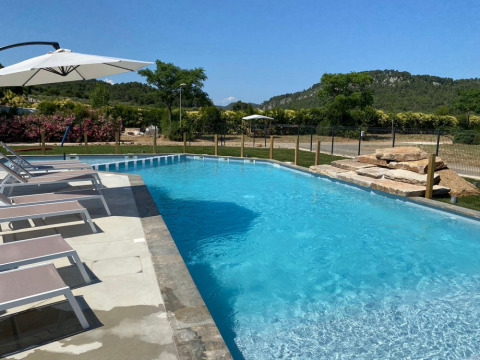 Udendørs swimmingpool med liggestole og parasoller på Camping De l'Olivigne i Occitanie, Frankrig.