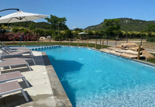Außenpool mit Liegestühlen und Sonnenschirmen im Camping De l'Olivigne in Occitanie, Frankreich.