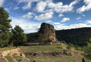Ruinas de piedra y paisaje en Camping De l'Olivigne en Occitania, Francia, bajo un cielo azul y nubes.