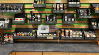 Scaffali con prodotti tipici, snack e bevande presso Camping De l'Olivigne, Occitania, Francia.