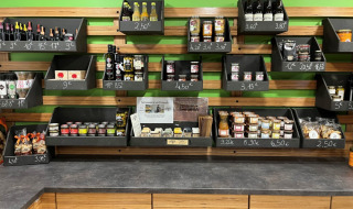 Hylder med lokale delikatesser, snacks og drikkevarer i receptionen på Camping De l'Olivigne, Occitanie.