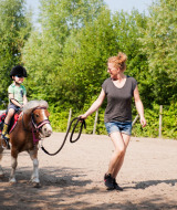 Un niño monta un pony guiado por una mujer en FarmCamps De Smulhoeve, un parque vacacional en Brabante Septentrional.